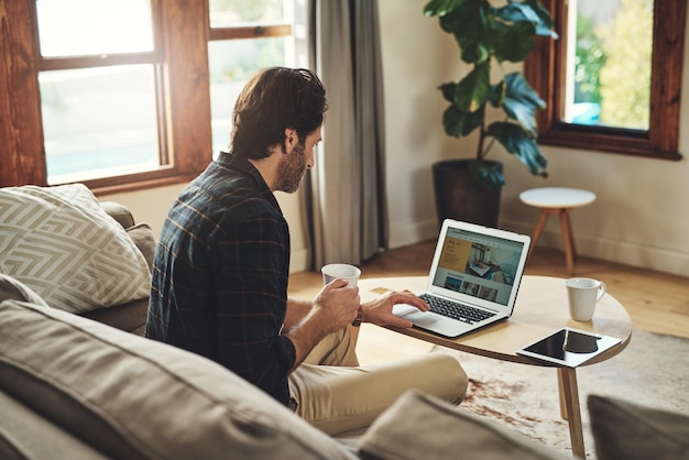 Photo remote work man and laptop in home with coffee blog and company review on internet male person small business and technology in living room for contact ecommerce and interior design on sofa