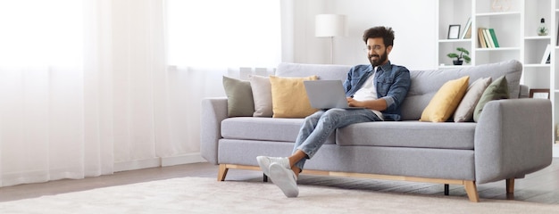 Remote work smiling indian freelancer guy working with laptop at home