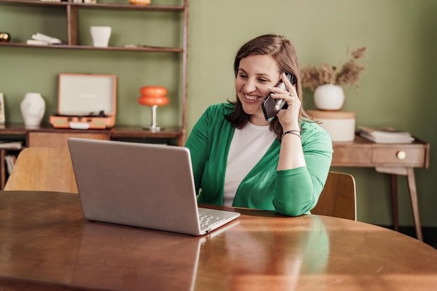 remotely a woman works at home online answers a phone call to a client Uses a laptop computer