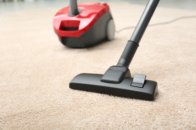 Removing dirt from carpet with modern vacuum cleaner indoors