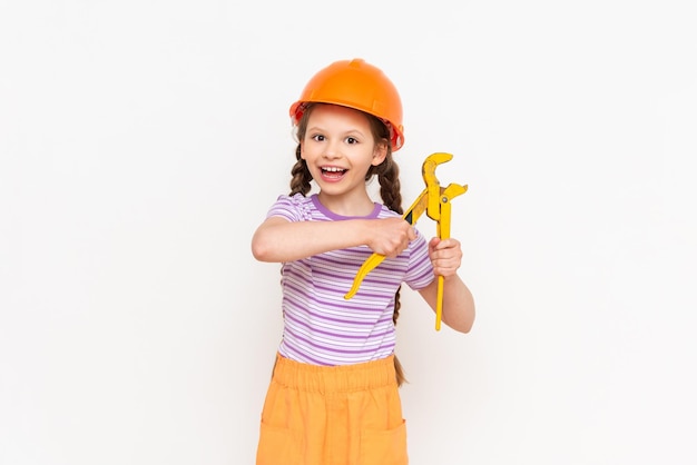 Renovation in the children's room A child in a construction helmet and a monkey wrench on a white isolated background Work as a builder choosing a profession for a child