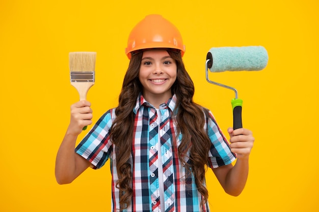 Renovation for childrens room Little girl in protective helmet and paint brush for painting walls