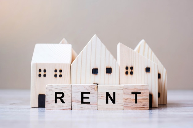 RENT cube blocks with wooden house model on table background.