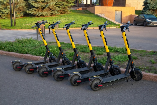 Rental scooters stand in a row on a city street