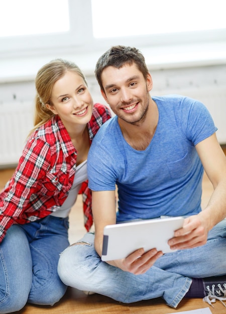 repair, building, renovation and home concept - smiling couple looking at tablet pc at home