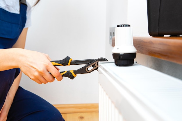 Repair heating radiator closeup woman repairing radiator with wrench