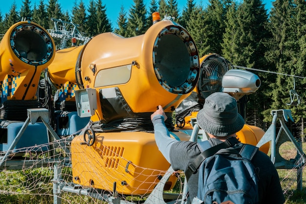 Repair man shows point finger on a snow making machine in the wood Huge device Control Check Nature Electricity Power