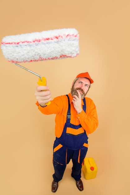 Photo repair professional painter in protective helmet happy painter man painter with painting roller