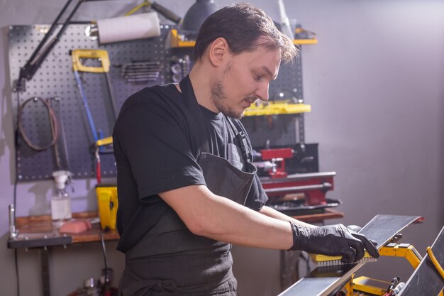 Repair, service and people concept - a man repairing the ski by rubbing a paraffin