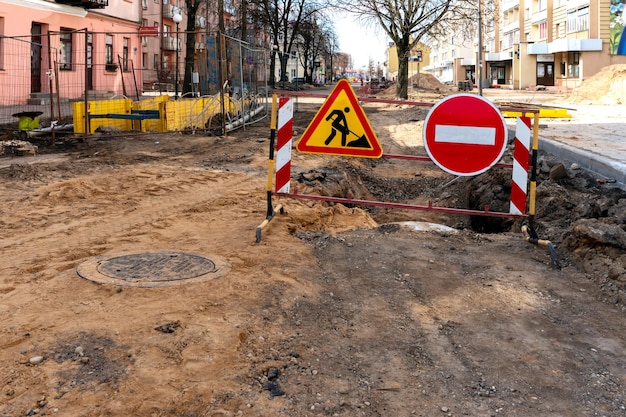 Repair of sidewalks and roads in the city A section of the street closed from traffic A road sign signifying a dangerous zone and prohibiting travel