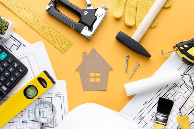 Repair tools and blue print surrounding cardboard house