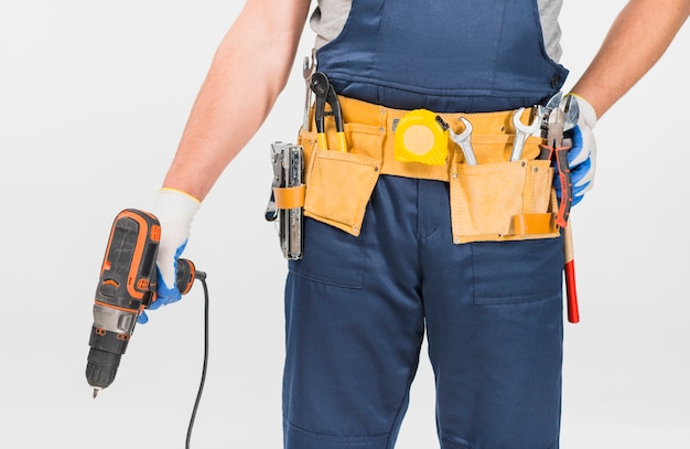 Repairman in blue overall holding drill 