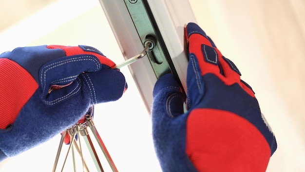 Repairman fixes windows or door locks with his tools closeup of hands of craftsman installing