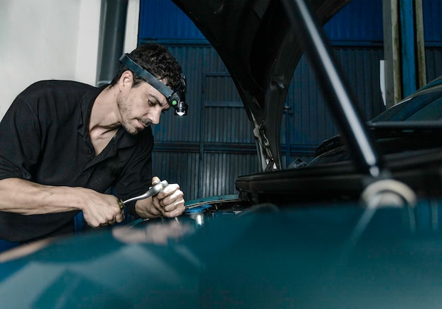 Repairman fixing engine of car in workshop