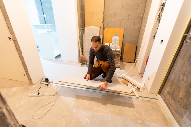 Repairman laying laminate flooring at home.