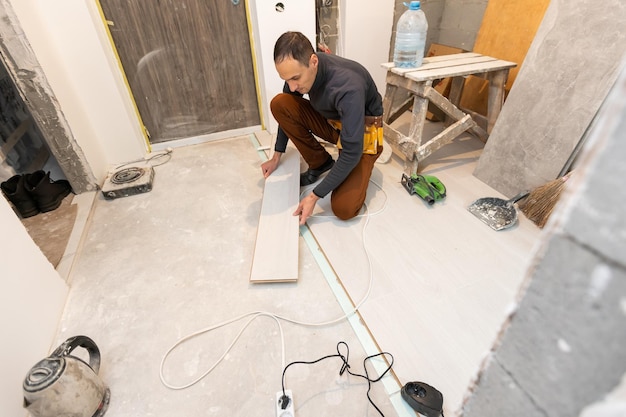 Repairman laying laminate flooring at home.