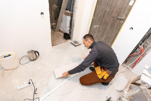 Repairman laying laminate flooring at home.