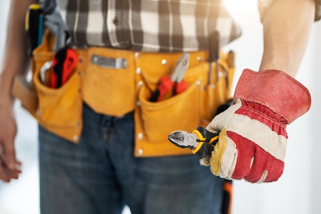 Repairman in mounting belt holding side cutters in his hand