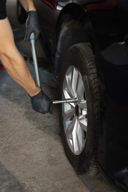 Repairman mounting wheel tire at service station car mechanic replacing a car wheel tire in garage