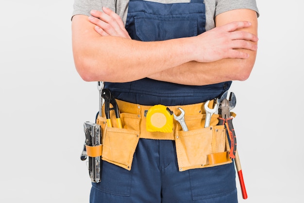 Repairman in overall standing with crossed arms 