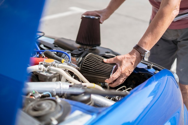 The repairman work with the car, replacing the cylinder intake air filter