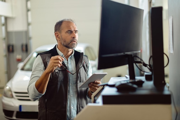 Repairman working on a computer while using touchpad in auto repair shop