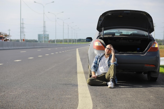 Replacing the wheel of a car on the road. A man doing tire work on the sidelines.