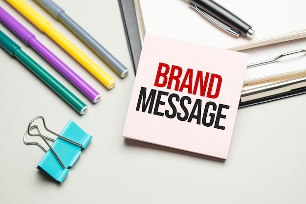 Reports and color charts are on the table. There are also red pens, pencil and paper in a black frame with the words BRAND MESSAGE. View from above