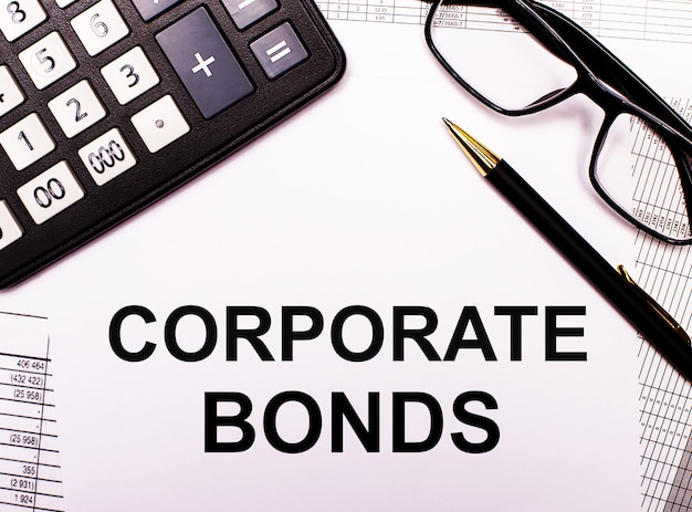 On the reports there is a calculator, glasses, a pen and a notebook with the inscription CORPORATE BONDS