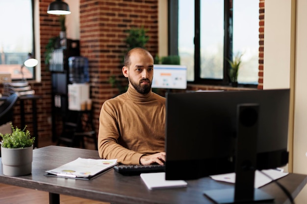 Research department team leader working on financial solutions while sitting at desk and using work computer. Startup project manager analyzing research results and accounting data.