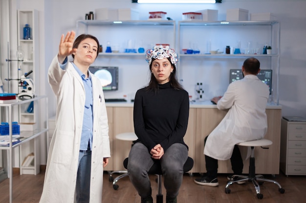 Researcher and patient with eeg headset looking at virtual display with touchscreen, virtual reality using medical inovation in neurological research lab. Scientists working with healthcare simulator.