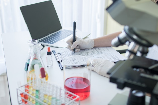 Researcher or scientist writing information result and note on paper in science lab