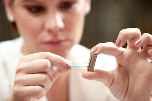 Residue might reveal the criminal A forensic scientist applying an ear bud to a bullet