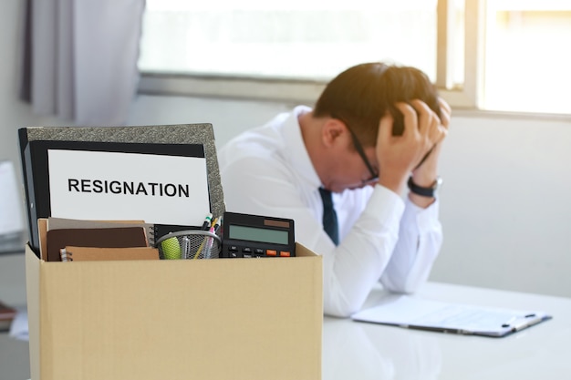 Resignation concept personal belongings and files in a brown cardboard box with resignation letter