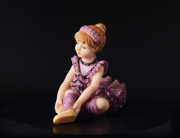 Photo resin figurine of a ballerina girl in purple tutu dress on black background