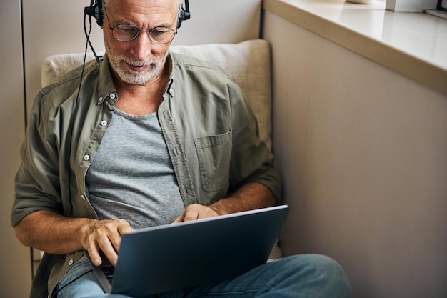 Responsible aged man in glasses working on his laptop