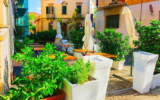 Restaurant in Corso Umberto I Street at Old city of Olbia on Sardinia Island in Italy. Tourists at cafes with tables in Town on Italian Sardegna. Mixed media.