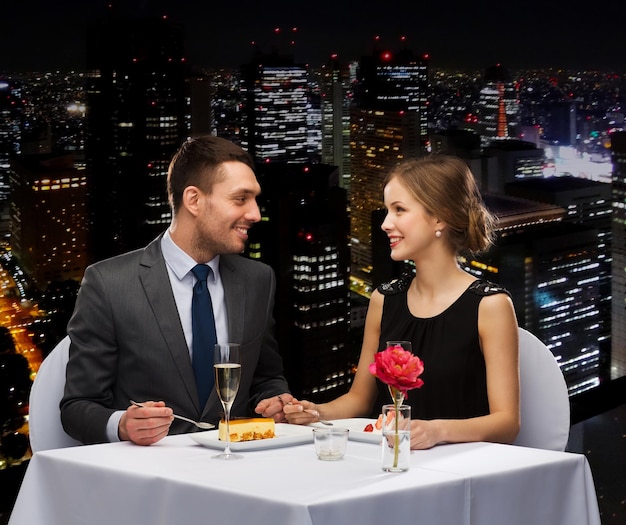 restaurant, couple and holiday concept - smiling couple eating dessert at restaurant