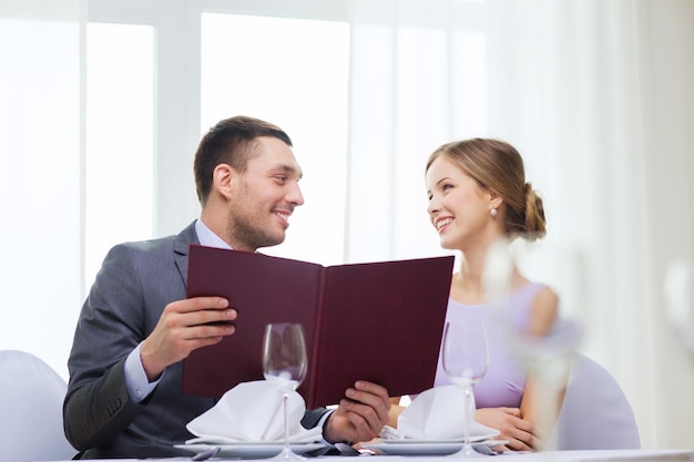 restaurant, couple and holiday concept - smiling couple with menu at restaurant