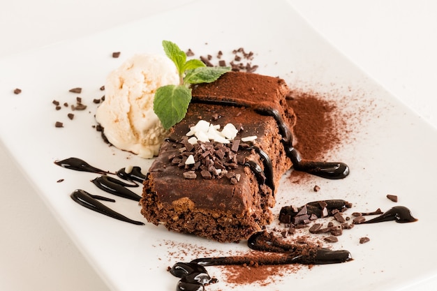 Restaurant dessert menu. Sweet brownie on white plate close up.