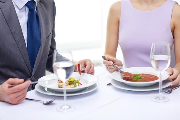 restaurant, food, people, date and holiday concept - close up of couple eating appetizers at restaurant