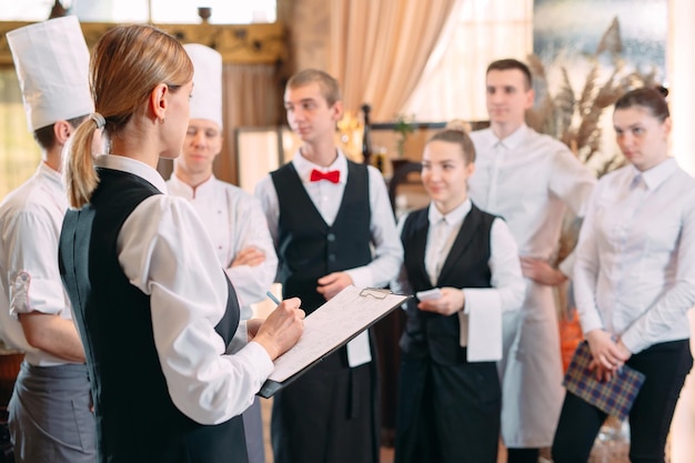 Restaurant manager and his staff in kitchen. interacting to head chef in commercial kitchen.