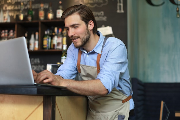 Restaurant manager working on laptop, counting profit.