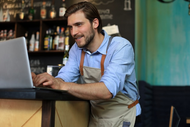 Restaurant manager working on laptop, counting profit.