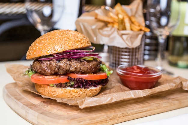 Restaurant serving dish - burger with cutlet with frying potato on wooden board