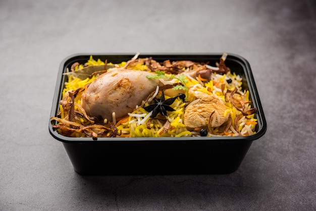 Restaurant style Chicken Tikka Biryani packed for home delivery in plastic box or container with Raita and salan