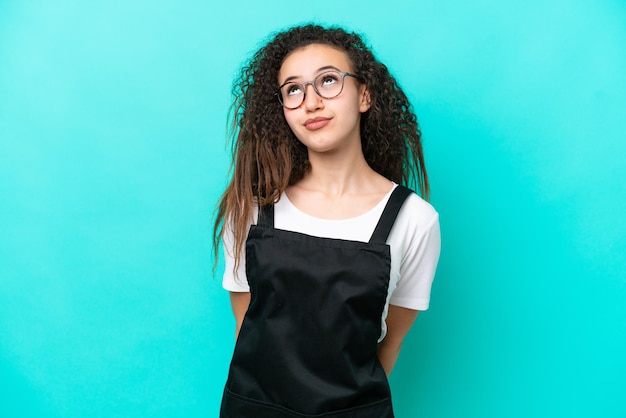 Restaurant waiter Arab woman isolated on blue background and looking up