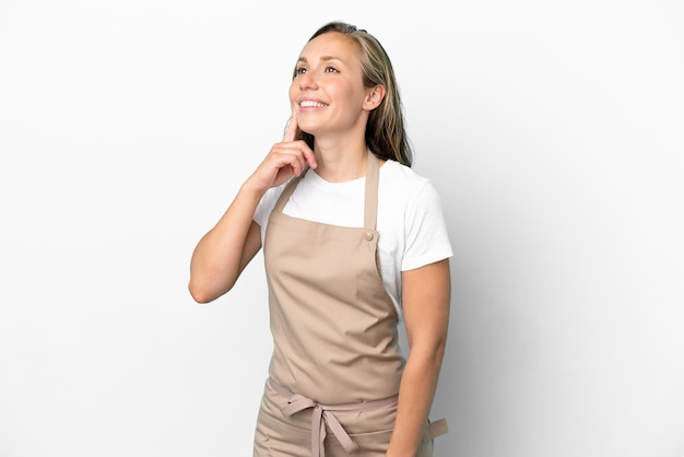 Restaurant waiter caucasian woman isolated on white background thinking an idea while looking up