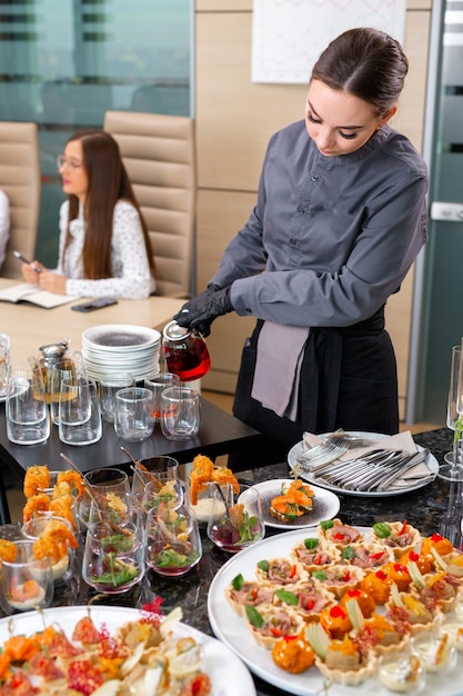 A restaurant waiter serves an offsite banquet in the officexA