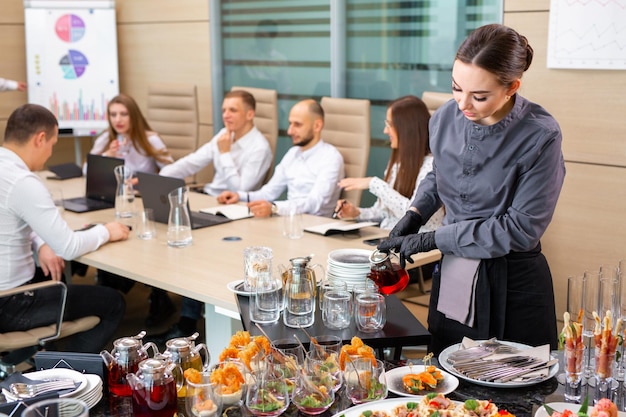 A restaurant waiter serves an offsite banquet in the officexA